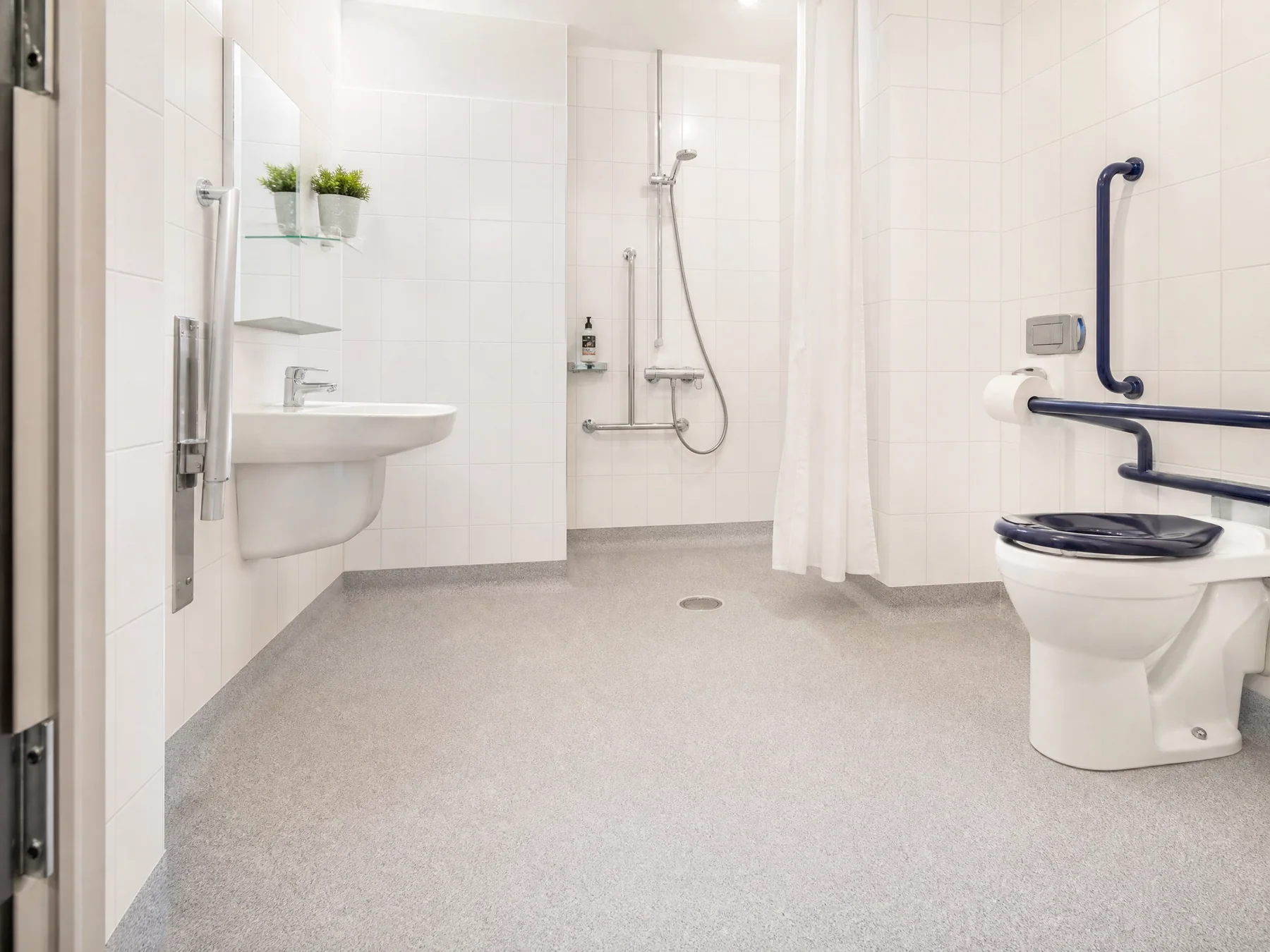 Completed accessible bathroom with continuous safety flooring and level shower area
